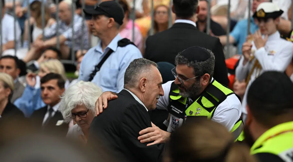 محمد فاتح الأحمد (في الوسط) والد أحمد الأحمد بطل حادثة إطلاق النار في بونداي يحضر وقفة إحياء ذكرى الضحايا والناجين من مجزرة بونداي في اليوم الوطني للتأمل على شاطئ بونداي في سيدني بأستراليا يوم 21 ديسمبر 2025 (إ.ب.أ)