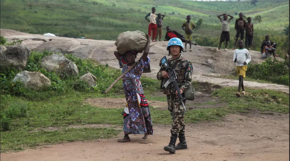 جندي من «بعثة الأمم المتحدة لتحقيق الاستقرار في الكونغو الديمقراطية» يصطحب امرأة كونغولية نازحة داخلياً (رويترز)