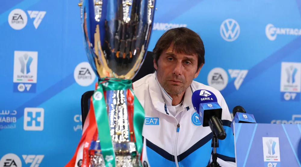 كونتي خلال المؤتمر الصحافي وأمامه كأس السوبر الإيطالي (رويترز)