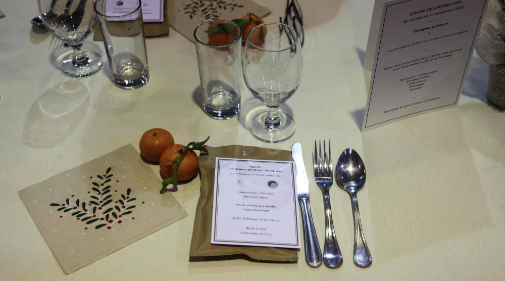 أدوات مائدة وقائمة طعام في انتظار حضور الرئيس الفرنسي إيمانويل ماكرون لعشاء الكريسماس مع جنوده في أبوظبي (أ.ف.ب)