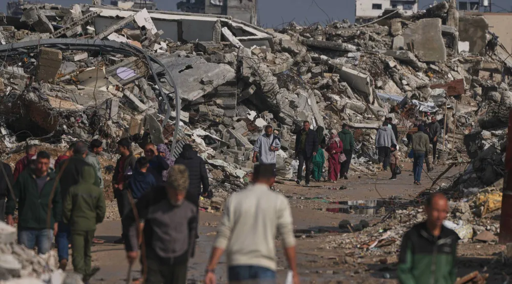 Palestinians walk along a street surrounded by buildings destroyed during Israeli air and ground operations in Gaza City, Wednesday, Dec. 17, 2025. (AP)