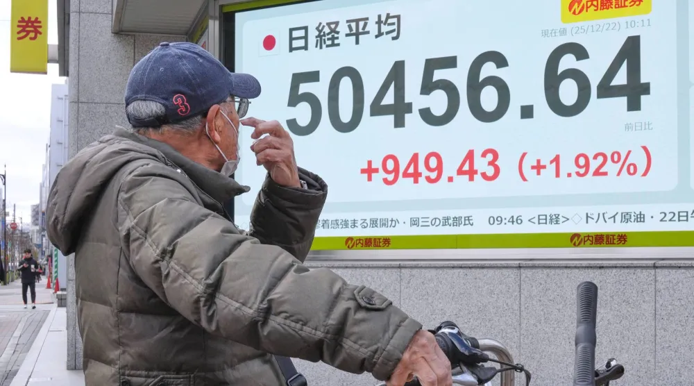 راكب دراجة ينظر إلى شاشة تعرض حركة الأسهم في وسط طوكيو (أ.ب)