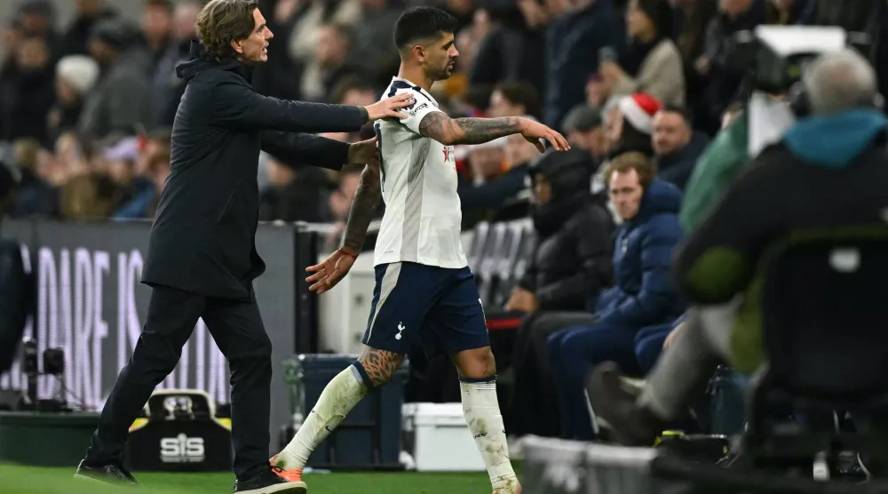 Tottenham Hotspur's Argentinian defender #17 Cristian Romero is ushered off the pitch by Tottenham Hotspur's Danish head coach Thomas Frank after becoming the second Tottenham player sent off during the English Premier League football match between Tottenham Hotspur and Liverpool at the Tottenham Hotspur Stadium in London, on December 20, 2025. (AFP)