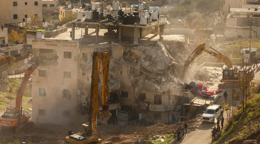 Israeli forces gather as an excavator demolishes a building built without a permit in the east Jerusalem neighborhood of Wadi Qaddum on December 22, 2025. (AFP)