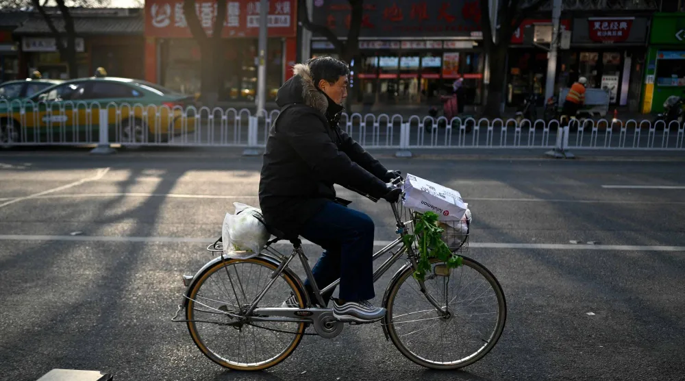 رجل يحمل مشتروات البقالة على دراجة في أحد شوارع العاصمة الصينية بكين (أ.ف.ب)