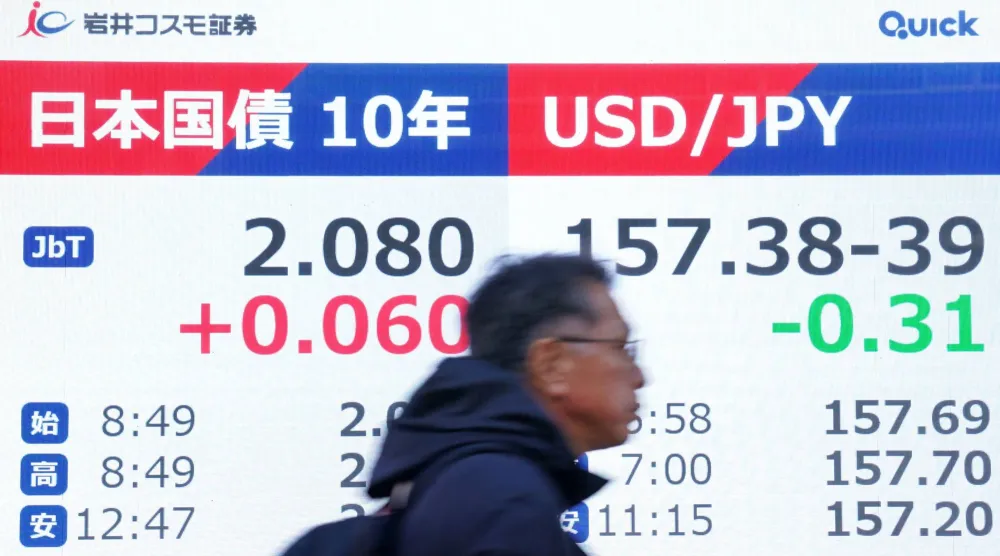 رجل يمر أمام شاشة تعرض سعر الين الياباني مقابل الدولار الأميركي وسط العاصمة طوكيو (أ.ف.ب)