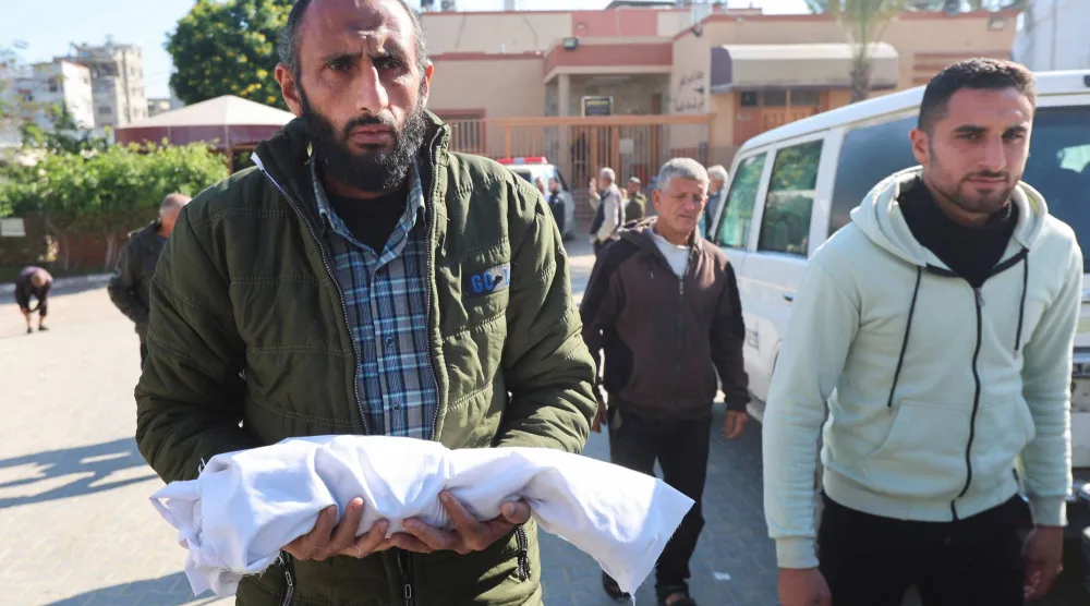 فلسطيني يحمل جثمان رضيع توفي بسبب البرد القارس في خان يونس جنوب غزة (رويترز)