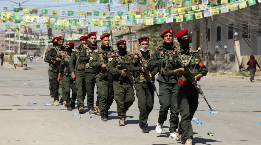 Suriye Demokratik Güçleri'ne (SDG) bağlı silahlı milisler, geçtiğimiz hafta çarşamba günü Suriye'nin Kamışlı kentinde ‘İrademizle devrimimizi koruyacağız’ sloganıyla düzenlenen gösteriye katıldı. (Reuters)