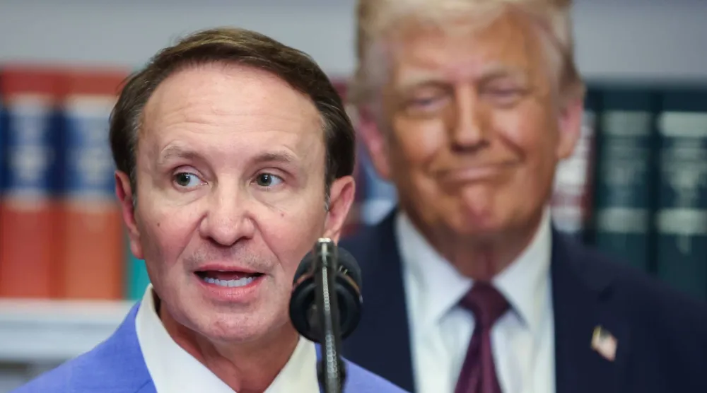 حاكم ولاية لويزيانا جيف لاندري يتحدث في البيت الأبيض بينما الرئيس الأميركي دونالد ترمب يستمع في الخلفية يوم 24 مارس 2025 (إ.ب.أ)