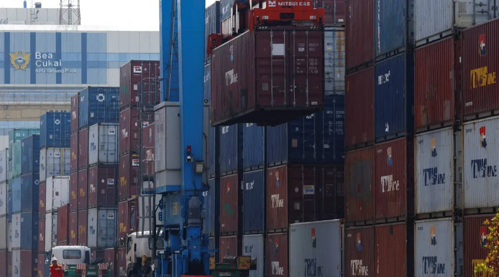 تسير شاحنة بجانب أكوام الحاويات في ميناء تانجونغ بريوك بمدينة جاكرتا (رويترز)