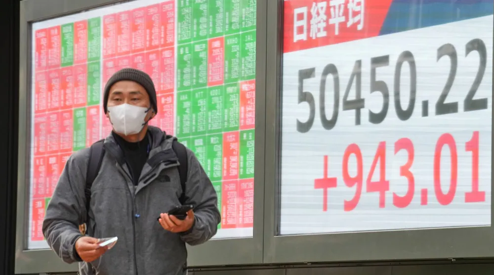 رجل يمر أمام لوحة إلكترونية تعرض حركة الأسهم وسط العاصمة اليابانية طوكيو (أ.ب)