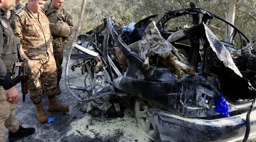 عناصر من الجيش اللبناني يعاينون السيارة التي تم استهدافها في بلدة عتقنيت (قضاء صيدا) وأدت إلى مقتل 3 أشخاص بينهم عنصر بالجيش اللبناني (إ.ب.أ)
