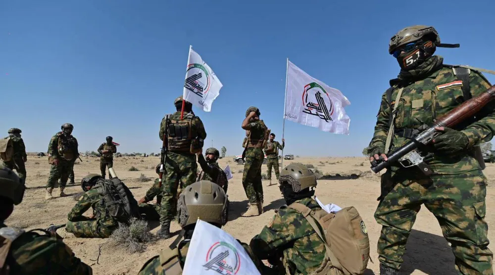 مقاتلون يرفعون شعار «الحشد الشعبي» خلال تدريبات عسكرية (أرشيفية-الحشد الشعبي)