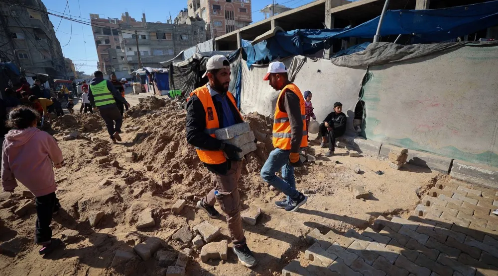 عمال البلدية الفلسطينيون يقومون بإصلاح طريق تضرر خلال الحرب في مخيم النصيرات للنازحين وسط قطاع غزة (أ.ف.ب)