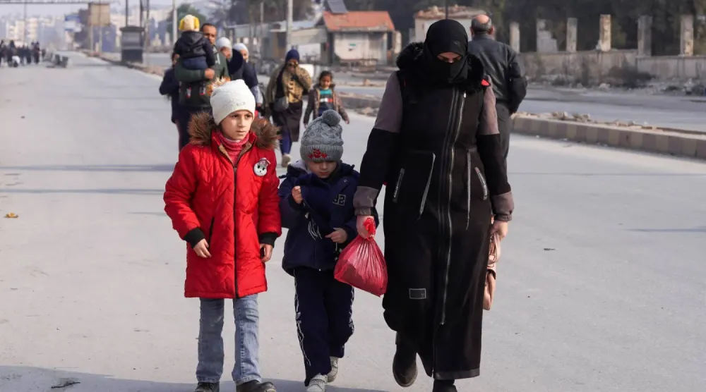 Şam ve SDG'nin pazartesi akşamı gerilimi azaltma konusunda anlaşmasının ardından Suriye, Halep'te iki çocuğuyla birlikte yürüyen bir kadın (Reuters)