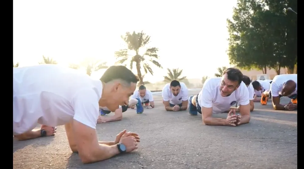 لقطة شاشة تُظهر الرئيس الفرنسي إيمانويل ماكرون (يمين) يقوم بتمارين رياضية برفقة جنود بلاده (إكس)