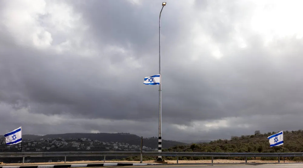 ترفرف الأعلام الإسرائيلية عند مدخل مستوطنة إيفياتار الإسرائيلية في الضفة الغربية المحتلة (رويترز)