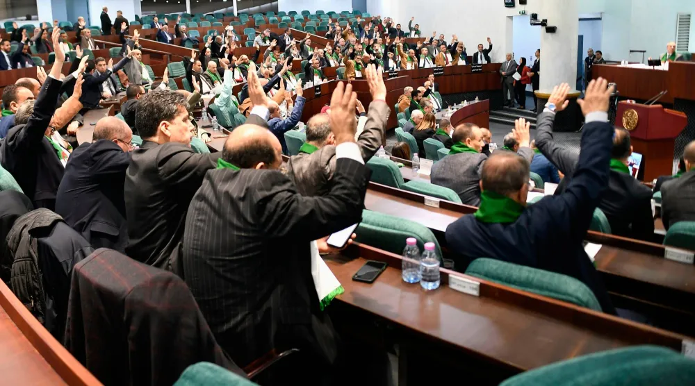 أعضاء البرلمان الجزائري خلال تصويتهم بالإجماع على قانون يجرّم الاستعمار الفرنسي للجزائر (أ.ب)