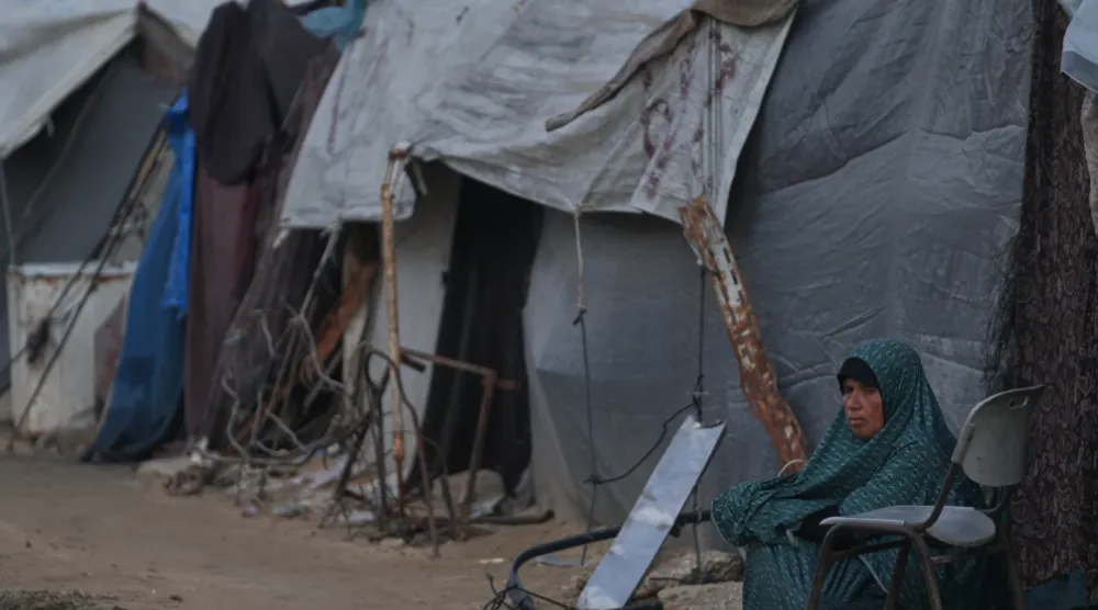 A woman sits next to her tent on an alley of a makeshift tent camp for displaced Palestinians in Deir al-Balah, central Gaza Strip, Tuesday, Dec. 23, 2025. (AP Photo/Abdel Kareem Hana)
