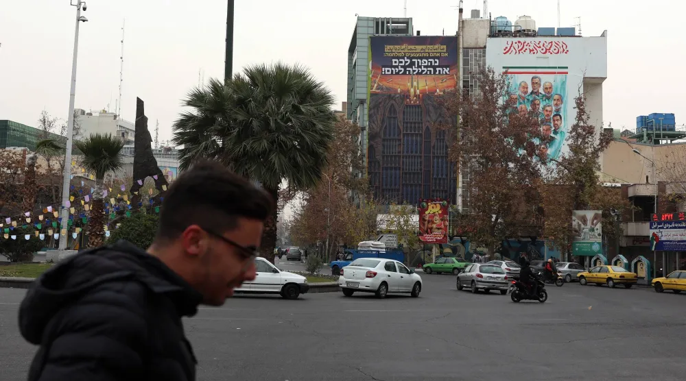 إيرانيون يمرون بجانب لوحة دعائية مناهِضة لإسرائيل تحمل عبارة باللغة الفارسية تقول: «نحن مستعدون. هل أنتم مستعدون؟» معلقة في ساحة فلسطين وسط طهران (إ.ب.أ)