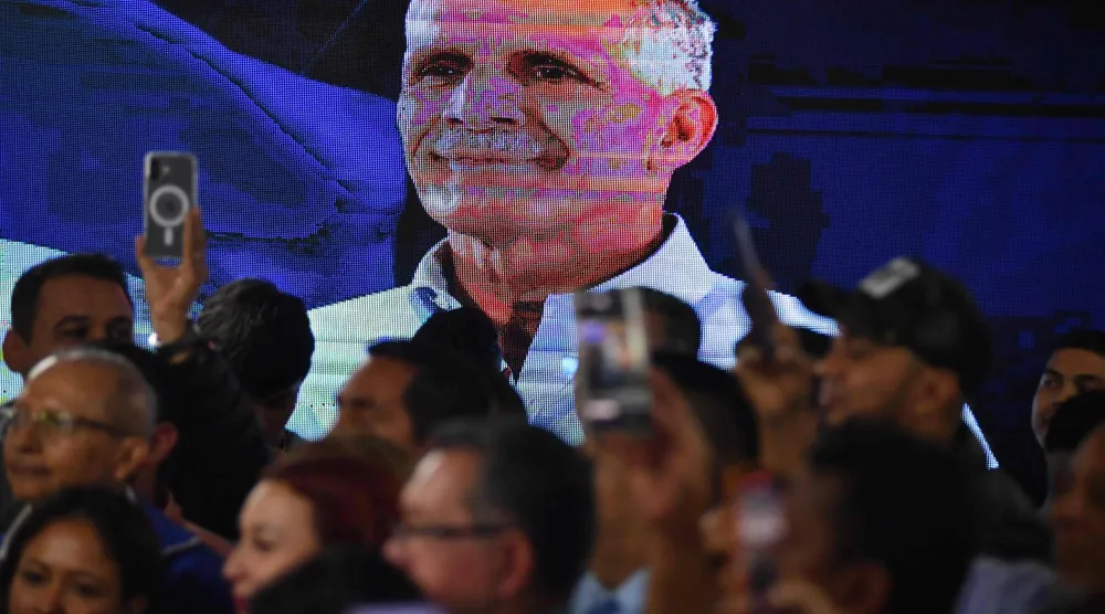 شاشة تعرض صورةً لنصري عصفورة وسط أنصاره (أ.ف.ب)
