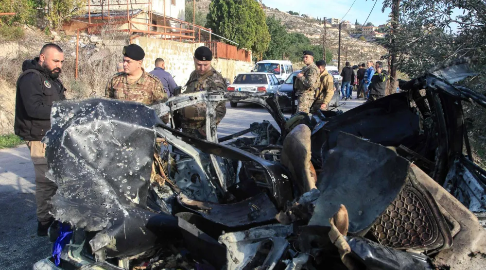 جنود من الجيش اللبناني يقفون بجوار حطام سيارة استُهدفت في غارة إسرائيلية على جنوب لبنان في 22 ديسمبر الحالي (أ.ف.ب)