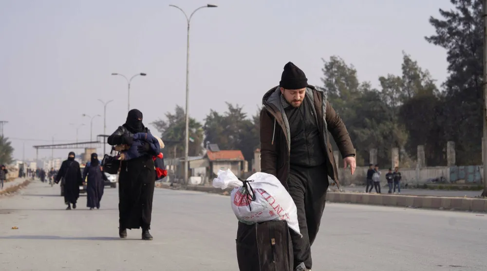 أشخاص مع أمتعتهم يسيرون على طول الطريق بعد أن اتفقت الحكومة السورية و«قوات سوريا الديمقراطية» على خفض التصعيد في مدينة حلب (رويترز)