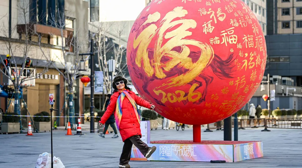 سيدة تستعد لالتقاط صورة تذكارية مع زينة العام الجديد في أحد الشوارع التجارية بالعاصمة الصينية بكين (أ.ف.ب)