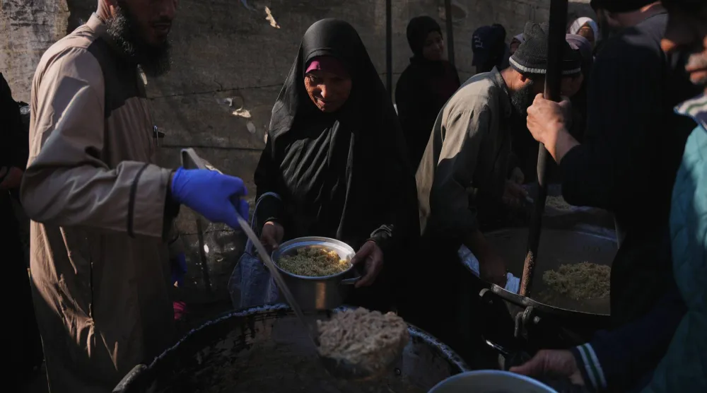 فلسطينية تتلقى طعاماً من مطبخ خيري في دير البلح وسط غزة يوم الخميس (أ.ب)