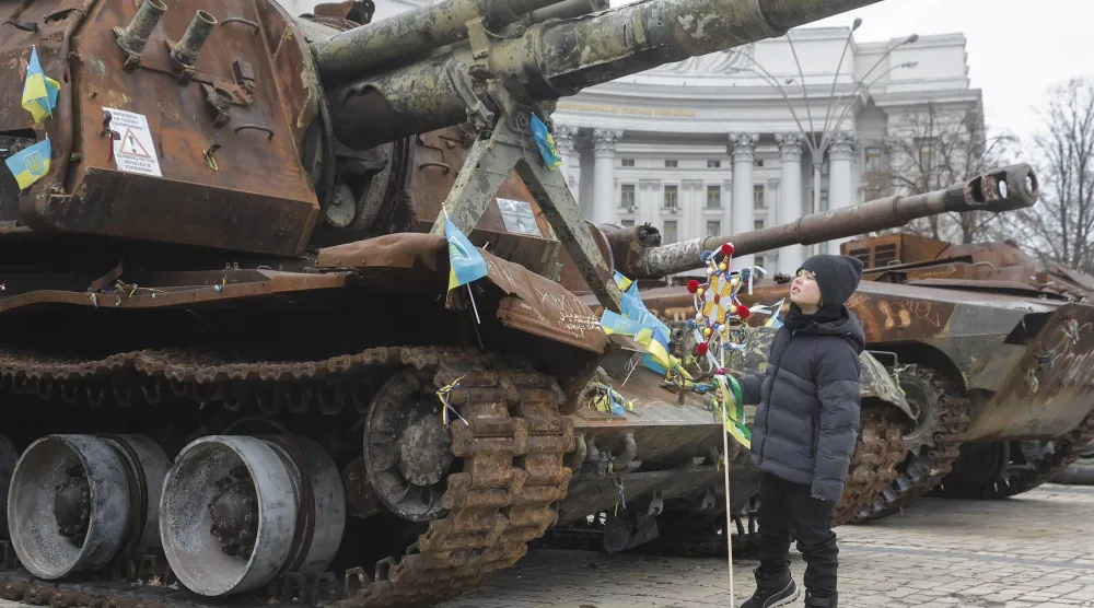 طفل يشارك في احتفالات عيد الميلاد ويبدو قرب دبابة روسية مدمرة في كييف يوم 25 ديسمبر (إ.ب.أ)