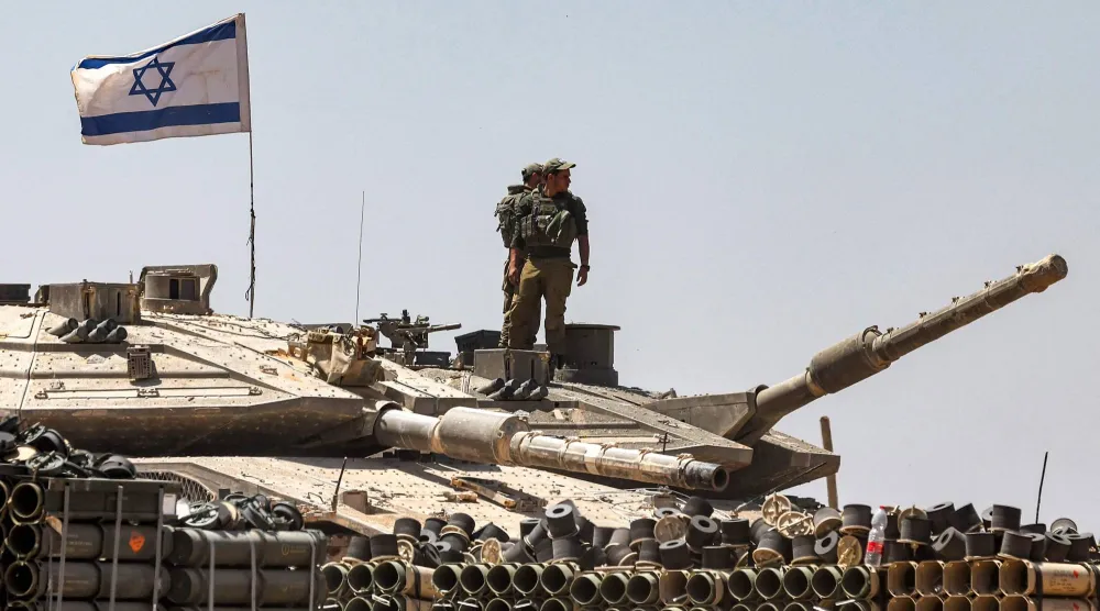 جنود من الجيش الإسرائيلي يقفون فوق برج دبابة متمركزة في جنوب إسرائيل بالقرب من الحدود مع قطاع غزة (أ.ف.ب)