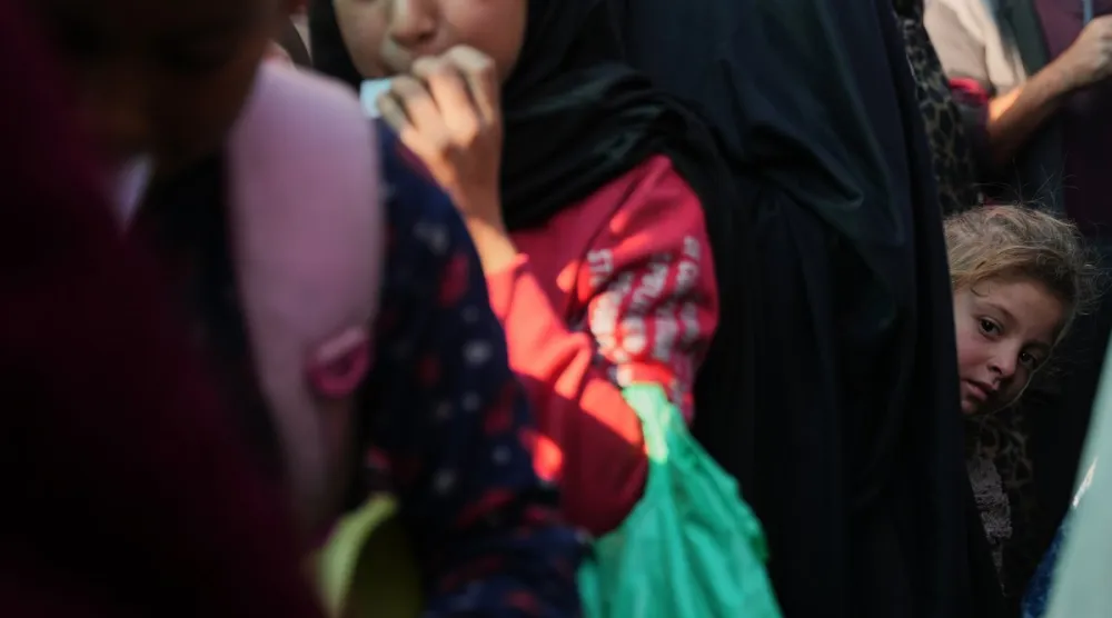 فتاة فلسطينية تقف بين صفوف المنتظرين لتلقي طعام من مطبخ خيري في دير البلح وسط غزة يوم الخميس (أ.ب)