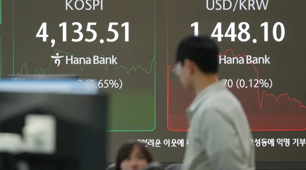 متداولون بالقرب من شاشات تعرض مؤشر «كوسبي» وسعر صرف الدولار مقابل الوون الكوري الجنوبي في بنك هانا بسيول (أ.ب)
