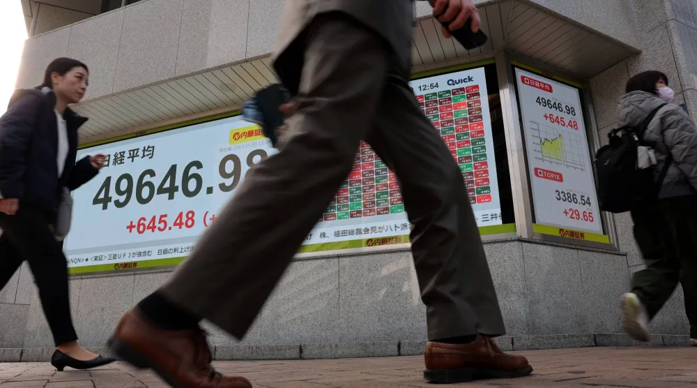 مشاة يمرون أمام شاشة إلكترونية تعرض حركة الأسهم في وسط العاصمة اليابانية طوكيو (رويترز)