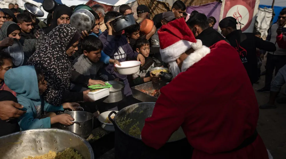 رجل بزي «سانتا كلوز» يشارك في مبادرة خيرية لتوزيع وجبات طعام لنازحين فلسطينيين بخان يونس الجمعة (إ.ب.أ)