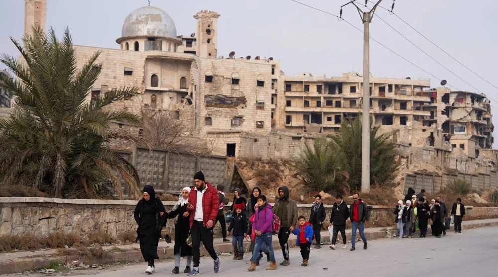 أشخاص يسيرون على طول طريق في حلب بعد موافقة «قسد» على خفض التصعيد الأسبوع الماضي (رويترز)