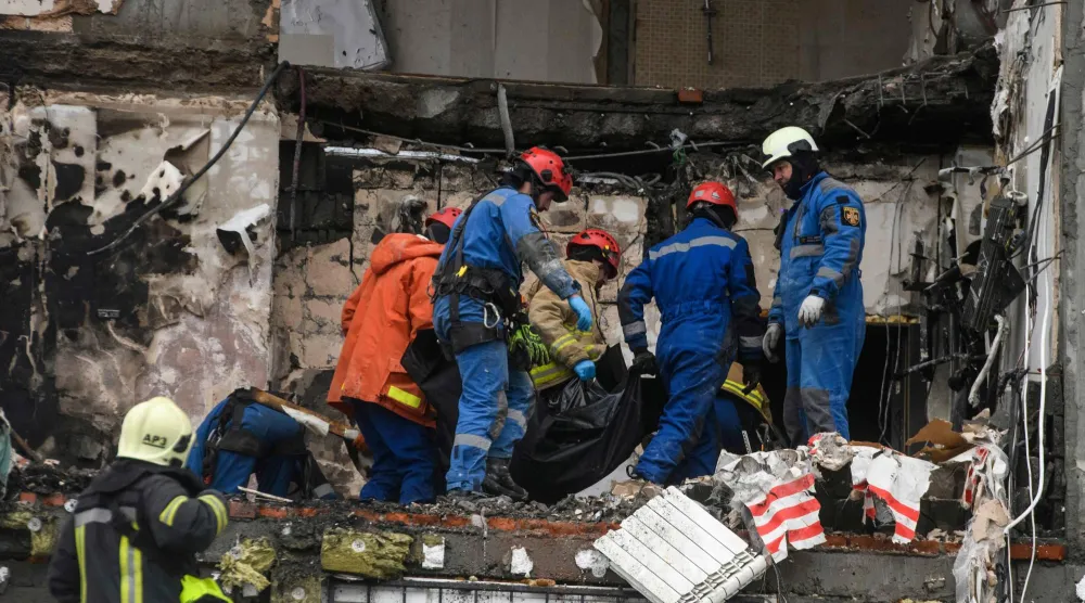 فريق إنقاذ يحمل جثمان أحد ضحايا الهجوم الروسي على كييف يوم 27 ديسمبر (أ.ف.ب)