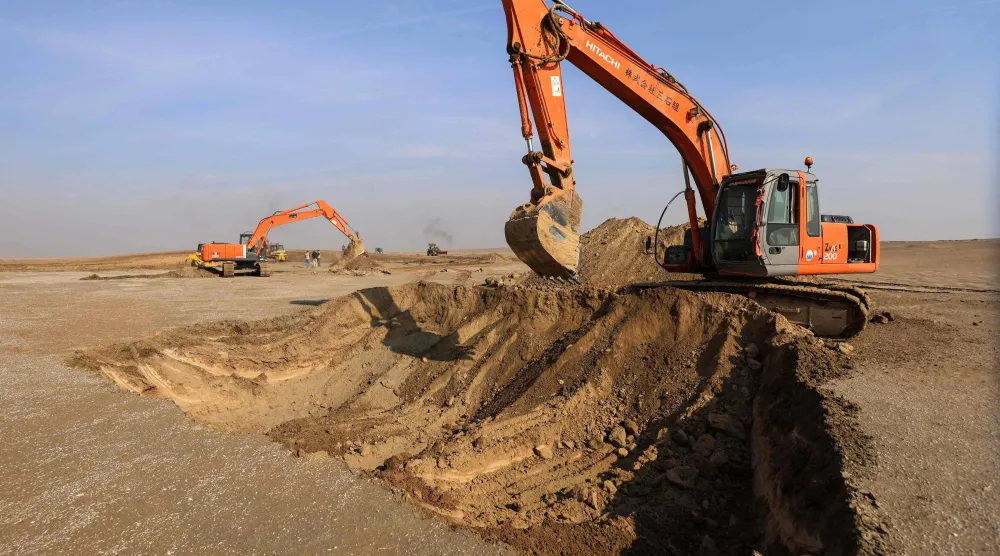 Excavators clear sand dunes and extract clay in the desert south of Samawah on December 21, 2025. (Photo by AHMAD AL-RUBAYE / AFP)