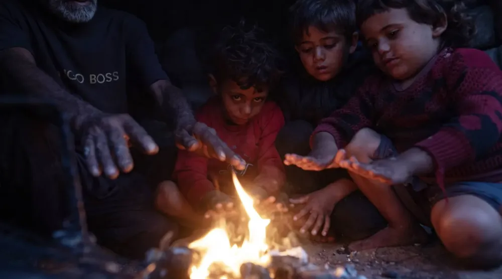 Dün Han Yunus’ta, barınaklarının dışında ateşin etrafında ısınmaya çalışan yerinden edilmiş Filistinli bir aile (EPA)