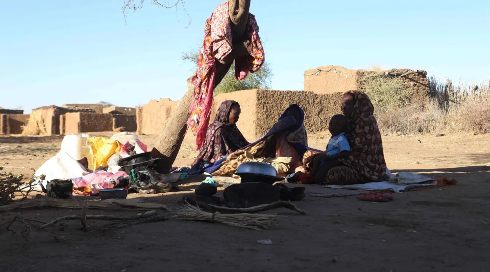 Sudanese displaced people who left El Fasher after its fall, sit in the shade in Tawila at the Rwanda camp reception point on December 17, 2025. (Photo by AFP)