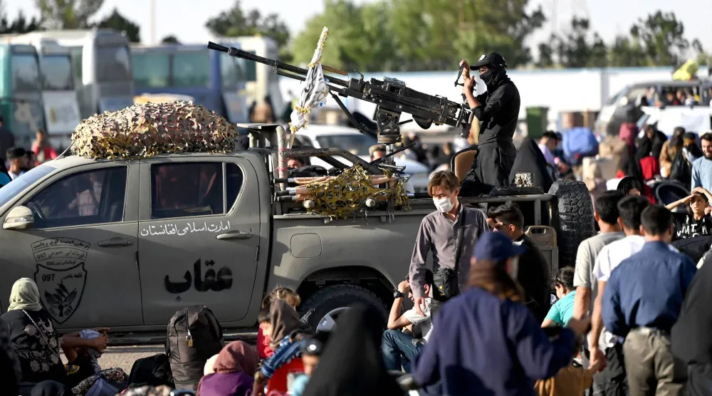 يقف أحد أفراد أمن «طالبان» على ظهر مركبة بينما يصل لاجئون أفغان إلى نقطة الصفر عند معبر إسلام قلعة الحدودي بين أفغانستان وإيران يوم 28 يونيو الماضي بعد ترحيلهم من إيران (أ.ف.ب)