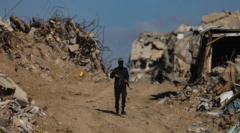 مقاتل من «كتائب القسام» التابعة لـ«حماس» يتابع البحث عن جثث رهائن إسرائيليين بمشاركة عناصر الصليب الأحمر وسط مخيم جباليا شمال غزة... 1 ديسمبر 2025 (إ.ب.أ)