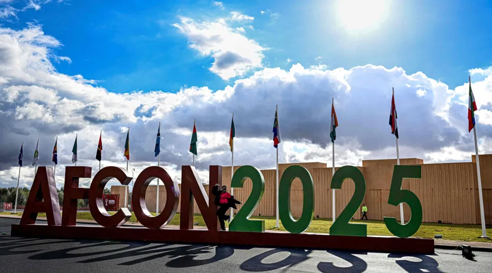 A woman poses for picture in front of AFCON 2025 symbol outside the Fan Zone in Marrakech city on December 25, 2025, during the Africa Cup of Nations (CAN) football tournament. (Photo by Khaled DESOUKI / AFP)