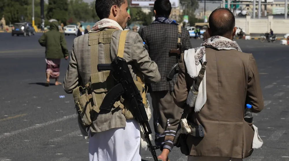 مسلحون حوثيون يسيرون في أحد شوارع العاصمة اليمنية المختطفة صنعاء (إ.ب.أ)