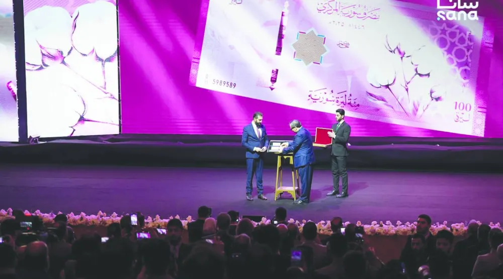 فئة الـ100 ليرة كما تبدو في الشاشة الخلفية في حفل إطلاق العملة السورية الجديدة بحضور الرئيس السوري وحاكم المصرف السوري (سانا)