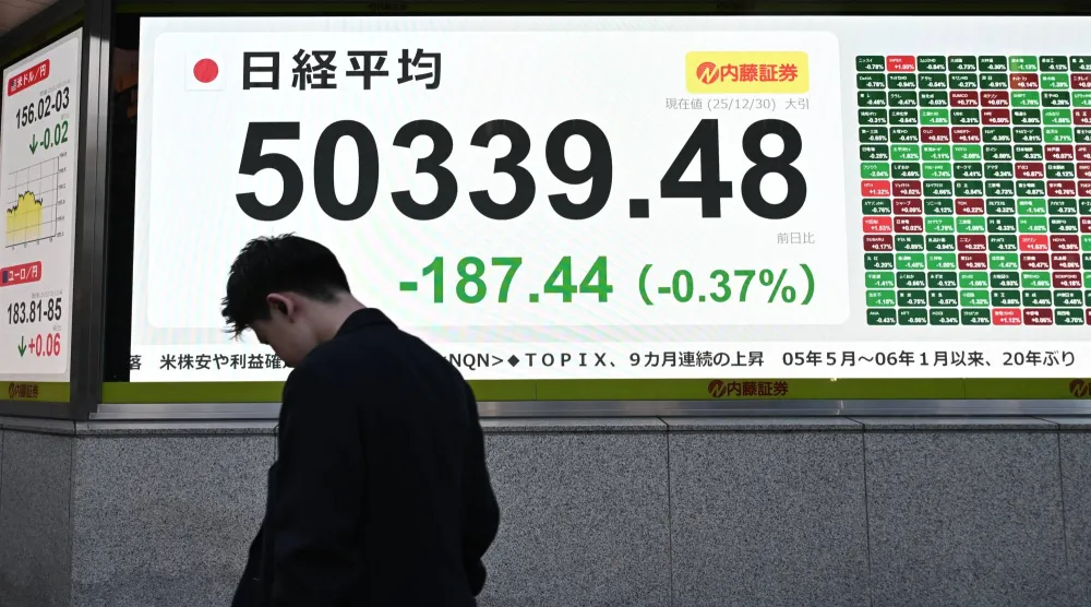 أحد المشاة يمر أمام شاشة إلكترونية تعرض حركة الأسهم في وسط العاصمة اليابانية طوكيو (إ.ب.أ)