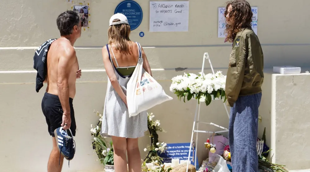 أفراد يقفون عند نُصب تذكاري لضحايا حادثة إطلاق النار في شاطئ بونداي بمركز الصحة النفسية في «بونداي بافيليون» (د.ب أ)