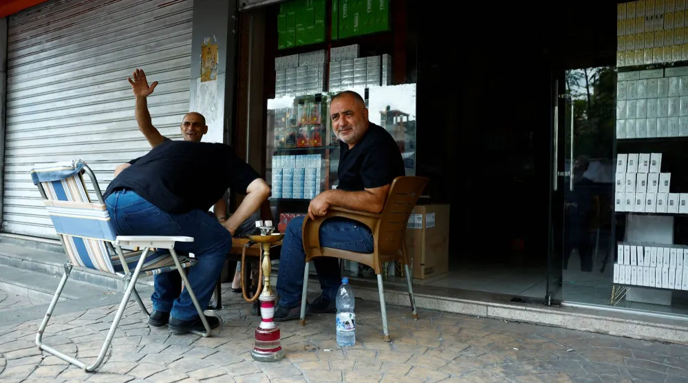 رجال يدخنون الشيشة خارج محل لبيع تبغ في ريف اللاذقية 25 سبتمبر (رويترز)