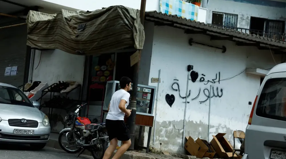 Geçtiğimiz eylül ayında Lazkiye vilayetinin Kardaha bölgesinde, ‘Özgür Suriye’ sloganının yazılı olduğu bir duvarın önünden geçen genç bir adam (Reuters)