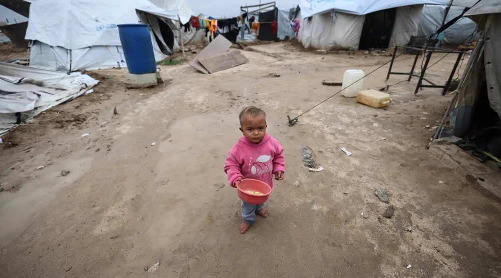 طفل يقف وسط ملاجئ مؤقتة للنازحين الفلسطينيين في مخيم البريج للاجئين وسط قطاع غزة (أ.ف.ب)
